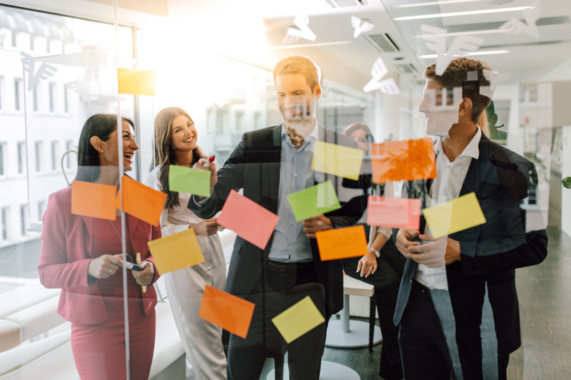 Mitarbeiter kleben Post-Its an Glasscheibe
